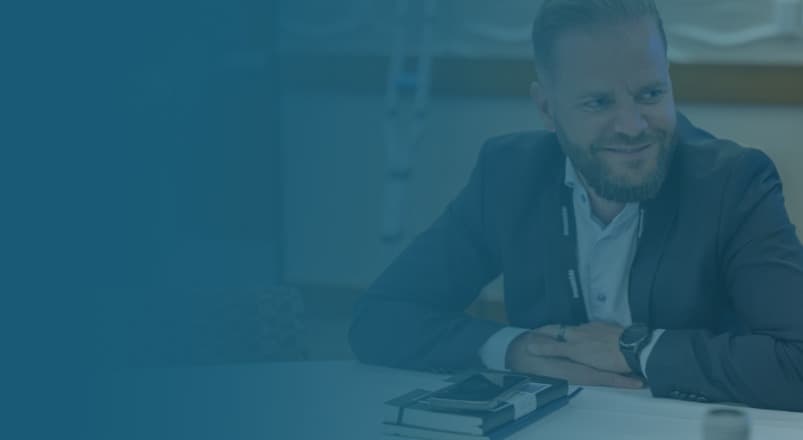 a man at a table with a book smiling